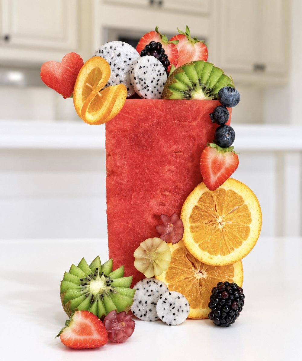 A carved watermelon tower layered with dragon fruit, kiwi, orange slices, strawberries and blackberries.