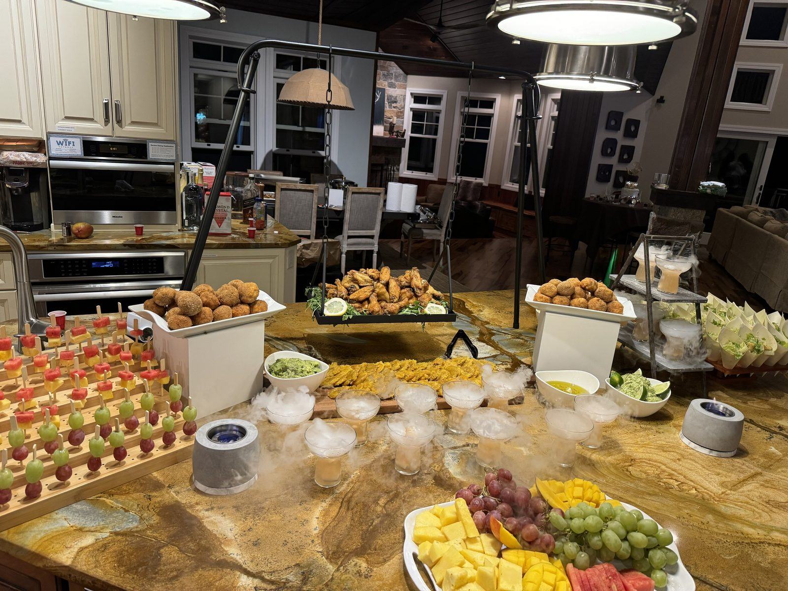 A Gastronomic Gala display: the hanging protein swing over sharing platters, fruit skewers, empanadas and dry-ice beverages.